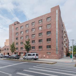A brick apartment building on a city street corner.