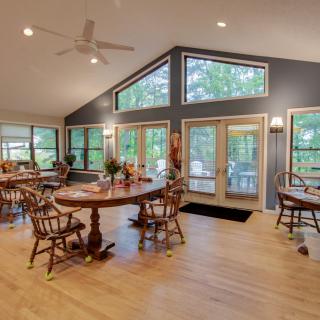 A spacious dining area with wooden furniture and large windows allowing natural light to fill the room.
