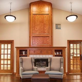 A cozy living room featuring a stylish seating arrangement and elegant wood paneling around a fireplace.