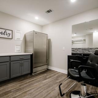 A modern and minimalist barbershop interior with a salon chair, large mirror, and well-lit space.