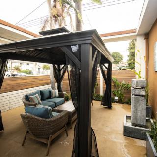 A stylish outdoor patio with a gazebo, comfortable seating, and modern decor.
