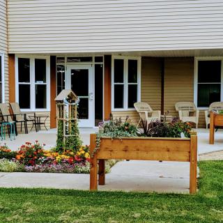 A cozy outdoor area with raised garden beds and seating in front of a building.