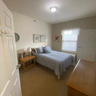 A cozy bedroom with a neatly made bed, nightstand, and dresser.