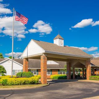 A welcoming entrance with an American flag under a bright blue sky and fluffy clouds.