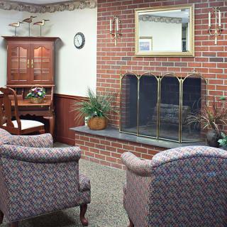 A cozy living room with a brick fireplace, armchairs, and tasteful decor.