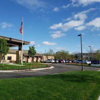 A sunny day outside a building with an American flag and parked cars.
