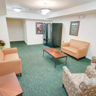 A cozy waiting area with sofas, a chair, and a vending machine.