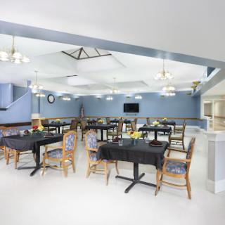 A modern dining area featuring neatly arranged tables and chairs under warm lighting.