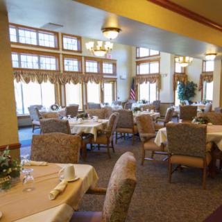 A spacious dining room with elegantly set tables and comfortable seating.
