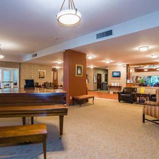 A spacious lobby with a piano and seating area, featuring warm lighting.