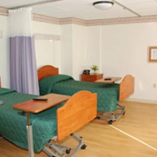 A hospital room with two beds and privacy curtains.
