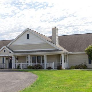 A suburban house with a large front porch and well-maintained lawn.