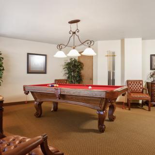 A cozy billiard room featuring a red-felt pool table and elegant decor.