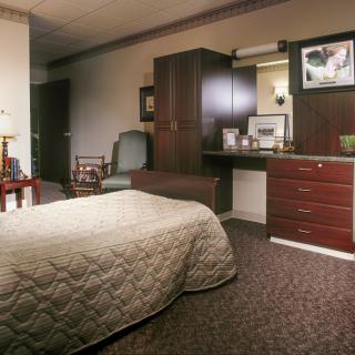 A cozy hotel room with a bed, armchair, and neatly arranged furniture.