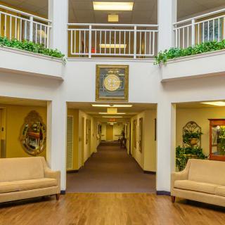 A well-lit lobby area with couches and a hallway leading to rooms.