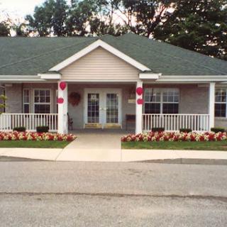 A charming residential building with a welcoming porch and beautifully landscaped front yard.