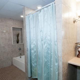A clean and modern bathroom with a bathtub and a blue shower curtain.
