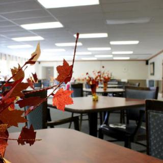 A spacious dining area decorated with autumn-themed centerpieces, featuring tables and chairs arranged for gatherings.