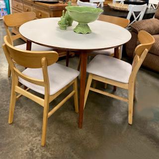 A stylish modern dining set featuring a round table and four wooden chairs.