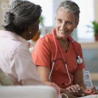 A nurse and a patient engaged in a friendly conversation during a medical consultation.