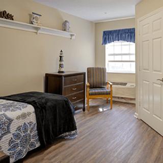 A cozy bedroom with a single bed, a dresser, and a chair by the window.