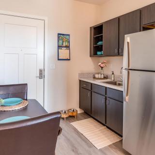A modern kitchen with dark cabinets and a dining table set for two.