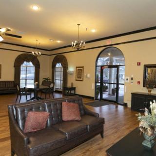 A cozy and elegantly decorated living room with a sofa, wooden floor, and large windows.