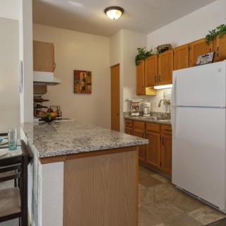 A compact kitchen with wooden cabinets, a white refrigerator, and a granite countertop.
