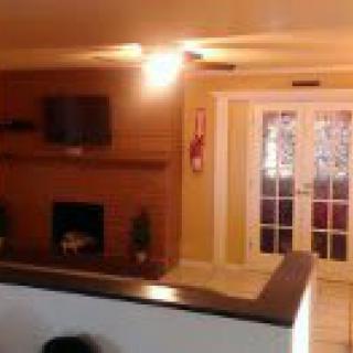 A cozy living room featuring a brick fireplace, wall-mounted TV, and French doors.