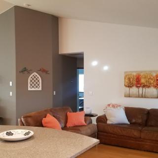 A contemporary living room featuring brown leather sofas with colorful cushions, modern wall art, and a neutral color scheme.