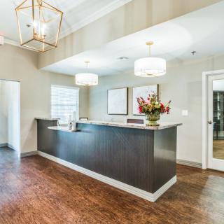 A modern reception area featuring a sleek desk, elegant lighting fixtures, and decorative flowers.