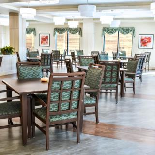 A spacious dining area with neatly arranged tables and chairs, featuring bright lighting and large windows.