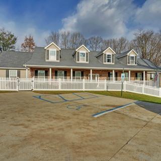 A suburban house with a white picket fence and a parking area in front, set against a cloudy sky.