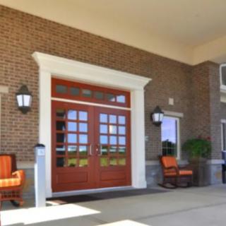 A building entrance with large double doors and seating on either side.