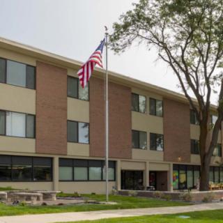 A brick residential building with a flagpole displaying the American flag in front.