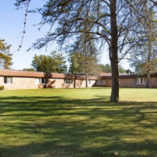 A peaceful outdoor view of a residential building surrounded by lush greenery and trees.