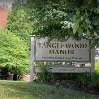 Entrance sign for Tanglewood Manor surrounded by greenery.