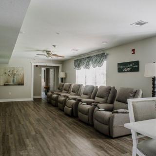 A spacious living room with a row of recliner chairs and elegant hardwood flooring.