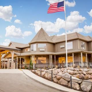 A hotel building with an American flag waving against a blue sky with clouds.