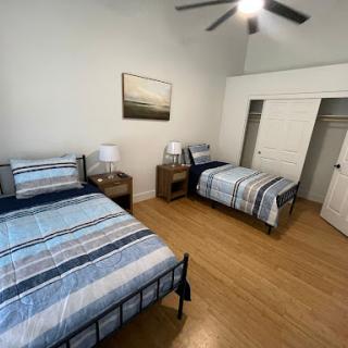 A cozy shared bedroom featuring two beds, nightstands, and ample natural light.