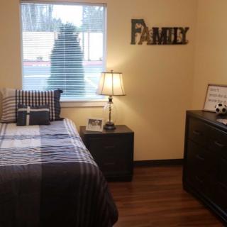 A cozy bedroom with a single bed, nightstand, and decorative 'Family' sign on the wall.