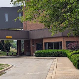 A view of the entrance to a building surrounded by green landscaping.
