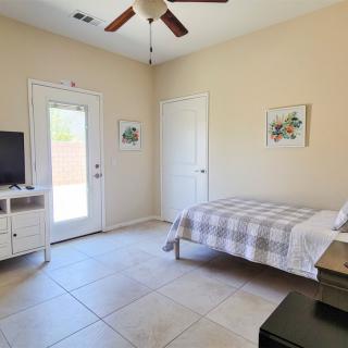 A minimalist bedroom with a single bed, neutral tones, and a wall-mounted TV.