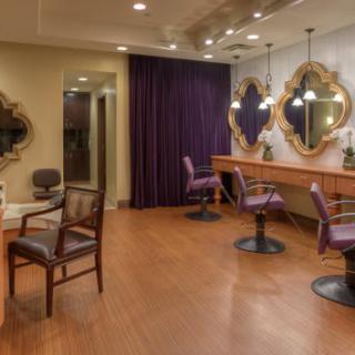 An elegant salon interior featuring chairs, mirrors, and soft lighting.