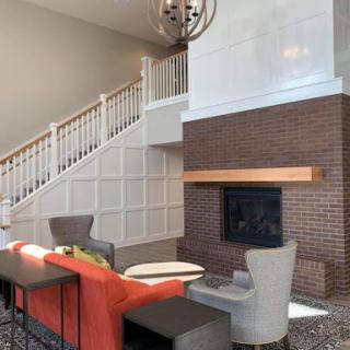 A modern living room featuring a cozy fireplace, elegant furniture, and a stylish staircase.