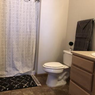 A clean and simple bathroom with a shower curtain, toilet, towel, and vanity cabinet.