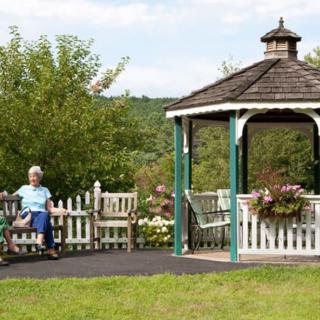 A peaceful garden scene featuring a gazebo and a person sitting on a bench.
