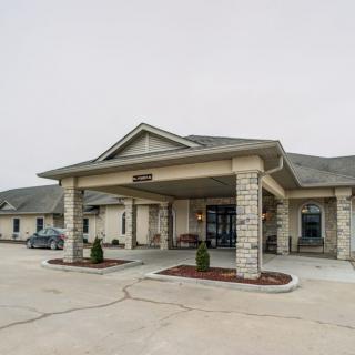 A front view of a building with a covered entrance and a parking lot.