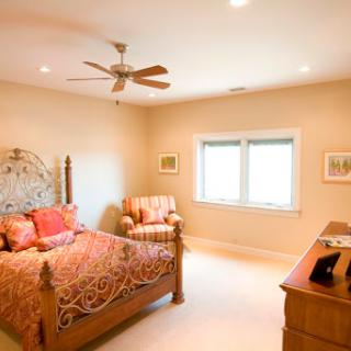 A cozy and well-lit bedroom featuring a stylish bed, comfortable chair, and natural light from the windows.