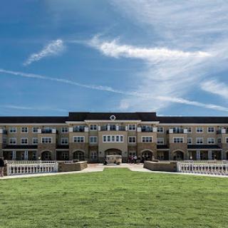 A modern building set against a clear blue sky, surrounded by well-maintained grass.